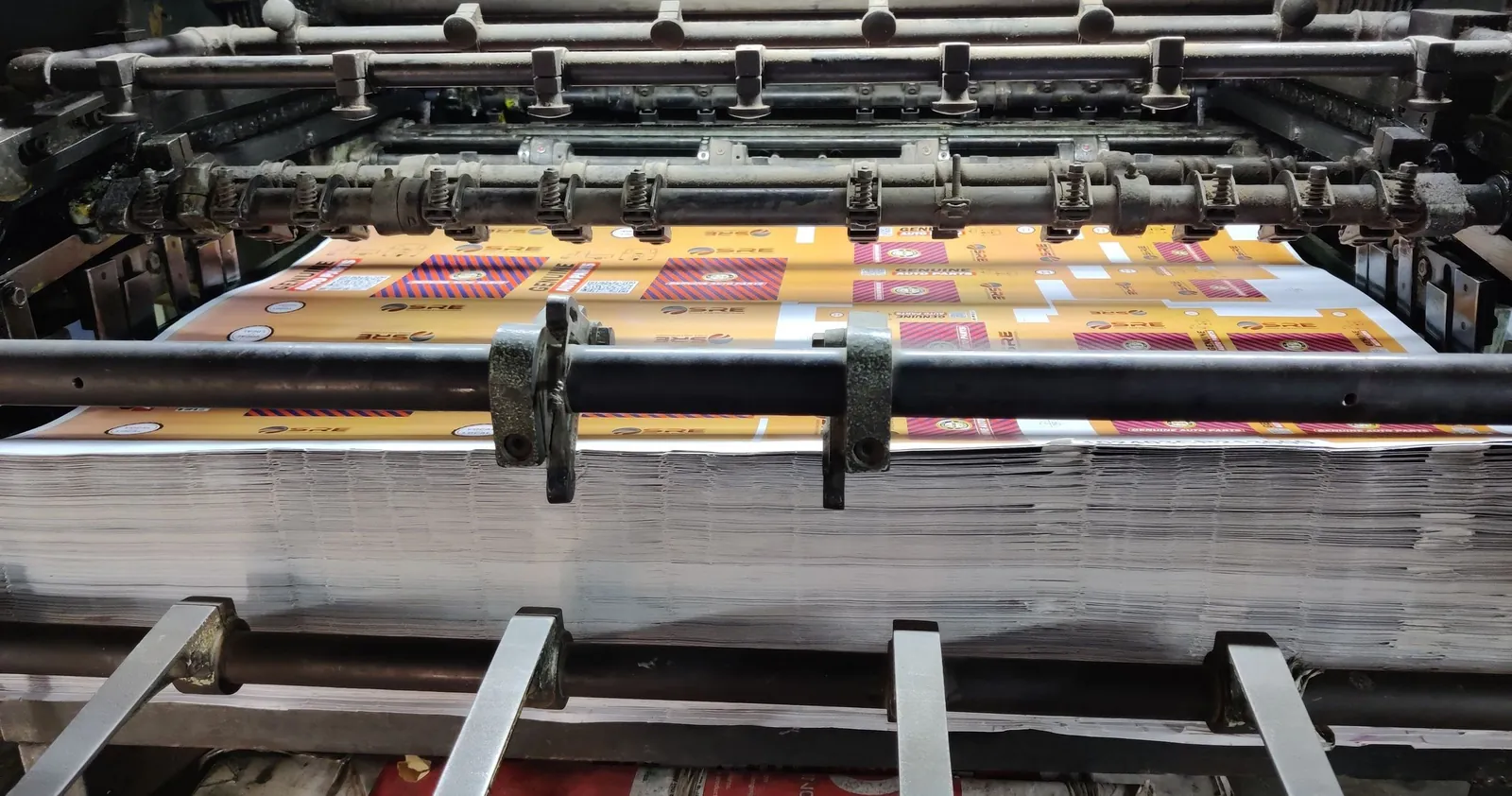 Máquina de impressão industrial rodando folhas coloridas, o processo por trás de um material impresso com qualidade de gráfica.